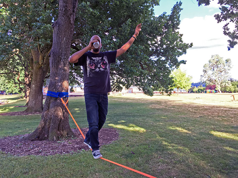 Alexis J. Villegas Drinking From a Cup While Slacklining at the Park